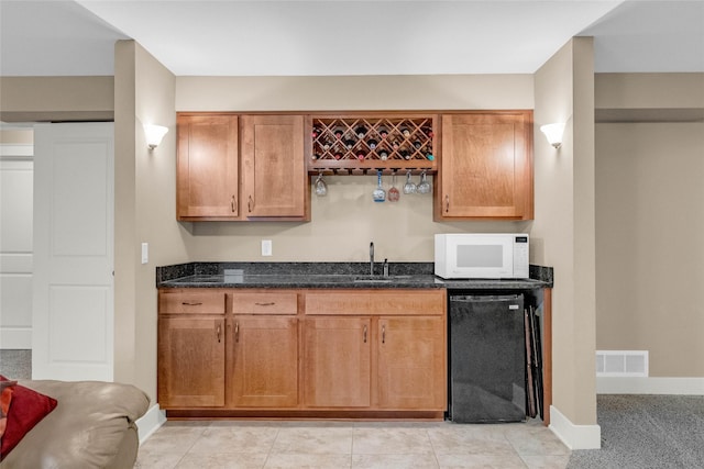 2501 NE Ewing Ct, Grimes, IA 50111 - kitchen with white microwave, dishwasher, dark stone countertops, and brown cabinetry