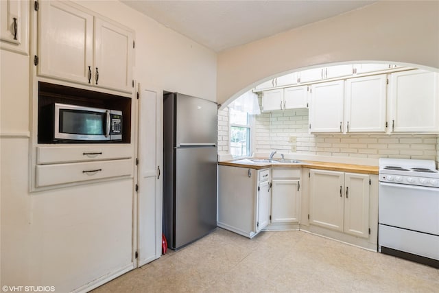 4512 Hickman Rd, Des Moines, IA 50310 - kitchen with stainless steel appliances, light countertops, backsplash, white cabinetry, and arched walkways