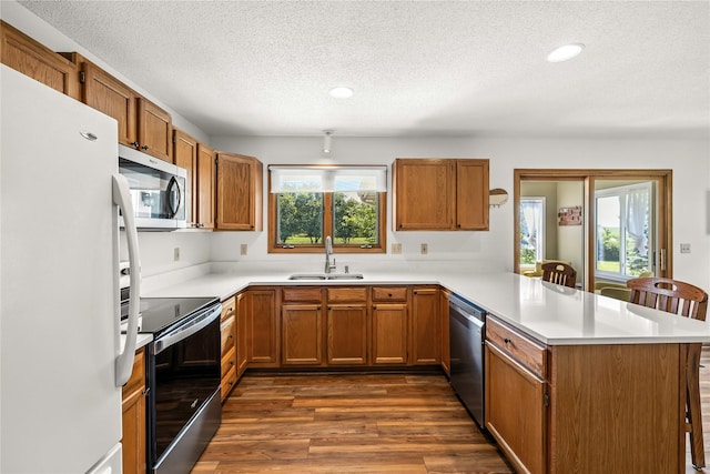 9421 NE 28th Ct, Ankeny, IA 50021 - kitchen featuring stainless steel appliances, a peninsula, a textured ceiling, dark wood finished floors, and light countertops