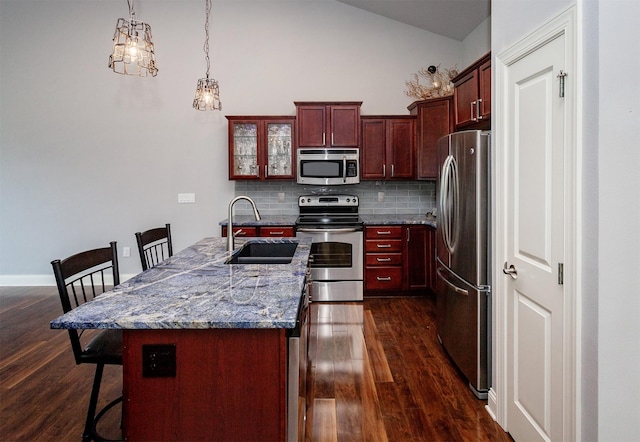 938 15th St SE, Altoona, IA 50009 - kitchen featuring appliances with stainless steel finishes, dark brown cabinets, dark wood-style floors, backsplash, and a breakfast bar area