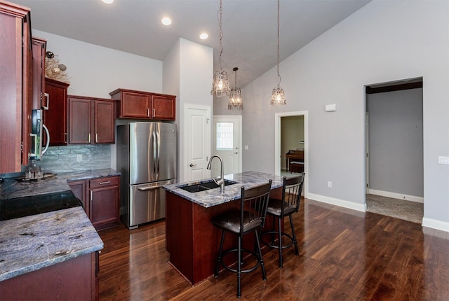 938 15th St SE, Altoona, IA 50009 - kitchen with stainless steel appliances, high vaulted ceiling, dark wood-style flooring, light stone countertops, and a kitchen island with sink