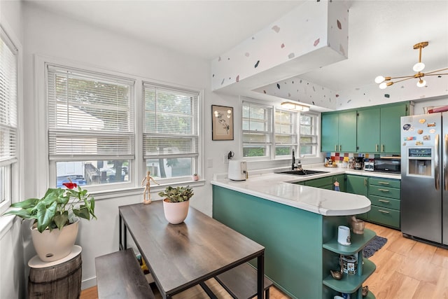 1416 Clinton Ave, Des Moines, IA 50313 - kitchen featuring stainless steel fridge, green cabinetry, a peninsula, and healthy amount of natural light