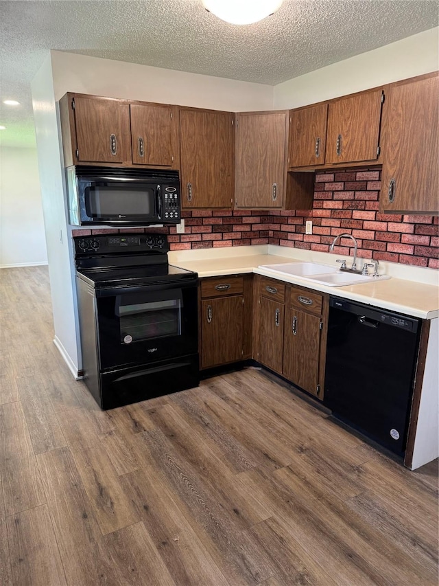 435 E Watrous Ave, Des Moines, IA 50315 - kitchen featuring black appliances, a textured ceiling, dark wood-style flooring, and light countertops
