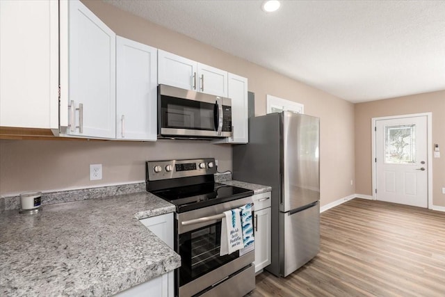 2311 Williams St, Des Moines, IA 50317 - kitchen with appliances with stainless steel finishes, white cabinetry, light wood-type flooring, and recessed lighting