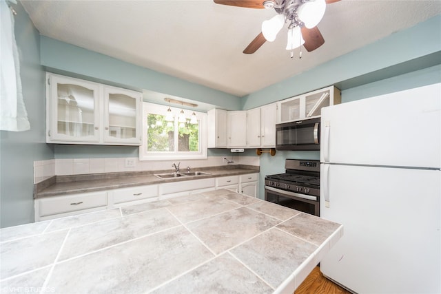 214 SW Scott St, Ankeny, IA 50023 - kitchen with stainless steel appliances, white cabinets, glass insert cabinets, ceiling fan, and tile countertops