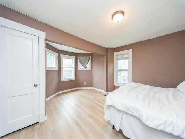 1534 9th St, Des Moines, IA 50314 - bedroom with light wood-style floors, multiple windows, and a textured ceiling