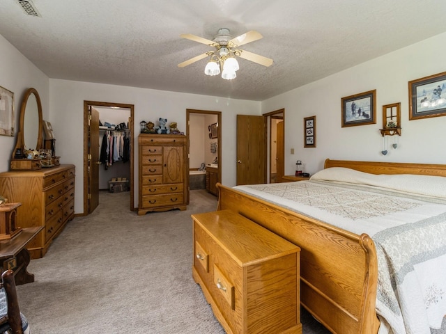 1439 N Shore Dr, Knoxville, IA 50138 - bedroom with light carpet, a spacious closet, a textured ceiling, connected bathroom, and ceiling fan
