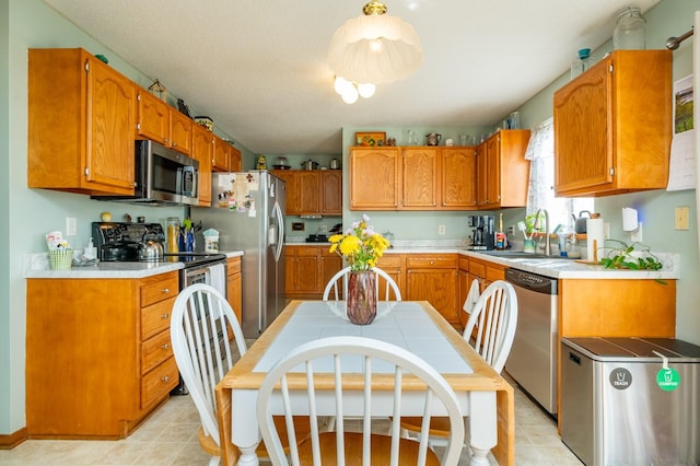 9102 NW Windsor Dr, Johnston, IA 50131 - kitchen featuring stainless steel appliances, brown cabinets, light countertops, and light tile patterned floors