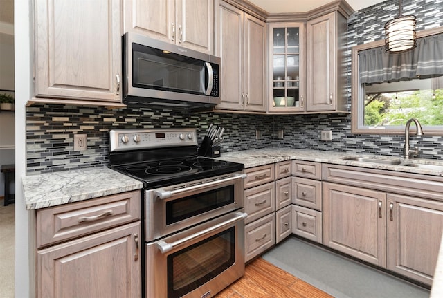 5526 Kensington Cir, Johnston, IA 50131 - kitchen with appliances with stainless steel finishes, tasteful backsplash, glass insert cabinets, light stone countertops, and light brown cabinetry