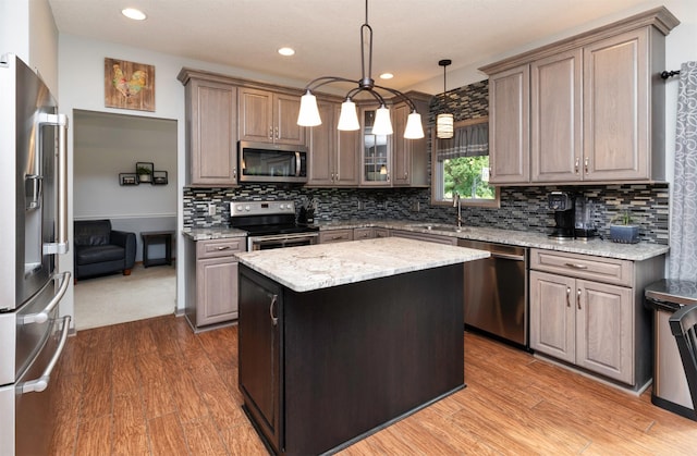 5526 Kensington Cir, Johnston, IA 50131 - kitchen featuring appliances with stainless steel finishes, wood finished floors, light stone countertops, a kitchen island, and recessed lighting