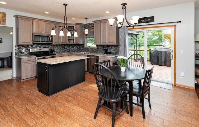 5526 Kensington Cir, Johnston, IA 50131 - kitchen featuring stainless steel appliances, a chandelier, a kitchen island, backsplash, and recessed lighting