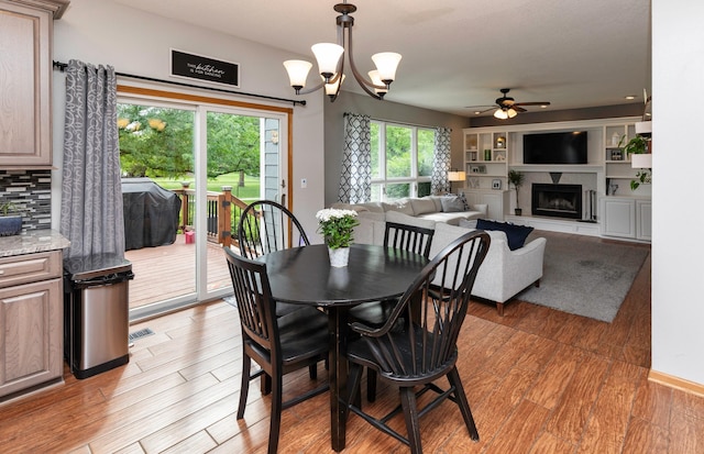 5526 Kensington Cir, Johnston, IA 50131 - dining room with ceiling fan, a fireplace with raised hearth, light wood-style floors, and a chandelier