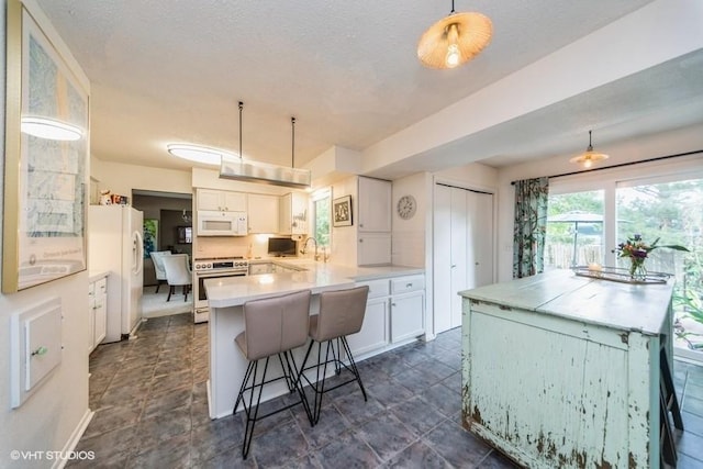 4505 75th St, Urbandale, IA 50322 - kitchen featuring white appliances, white cabinets, light countertops, a kitchen breakfast bar, and a textured ceiling