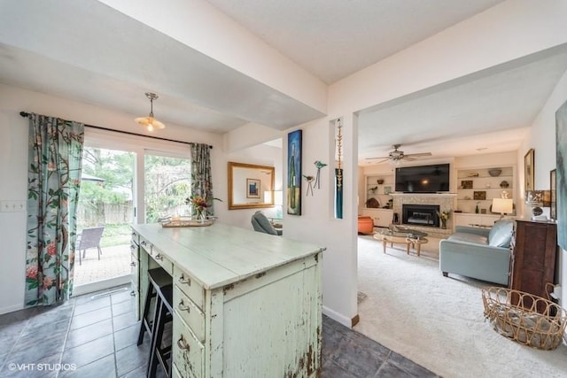 4505 75th St, Urbandale, IA 50322 - kitchen featuring a glass covered fireplace, light countertops, a ceiling fan, open floor plan, and pendant lighting