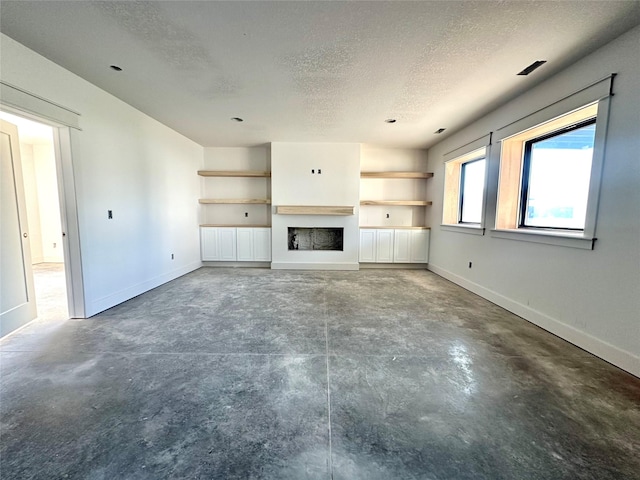 880 Harrington Way, Waukee, IA 50263 - unfurnished living room featuring a textured ceiling, concrete flooring, and a fireplace