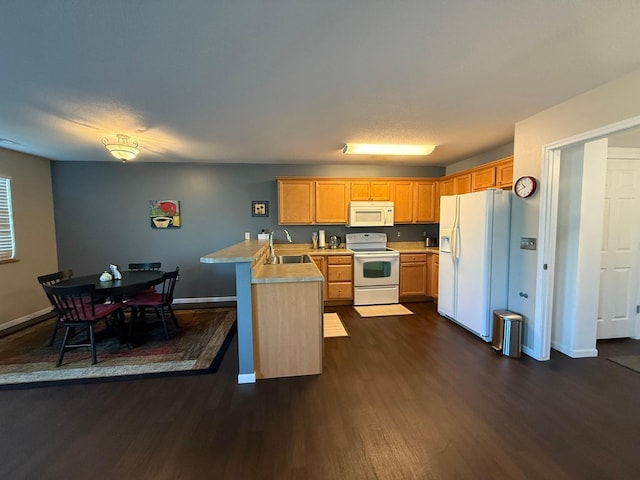 244 4th Ave W, Grinnell, IA 50112 - kitchen featuring white appliances, a peninsula, dark wood finished floors, light countertops, and a breakfast bar area