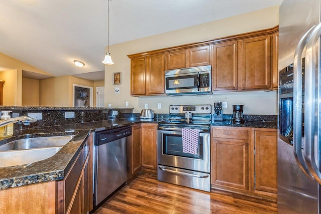 1870 SE Oxford Dr, Waukee, IA 50263 - kitchen with stainless steel appliances, dark wood-style floors, brown cabinetry, decorative light fixtures, and dark stone countertops
