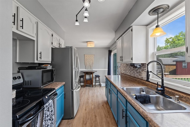 6675 NW 5th St, Des Moines, IA 50313 - kitchen featuring appliances with stainless steel finishes, blue cabinetry, white cabinetry, light wood-type flooring, and decorative light fixtures