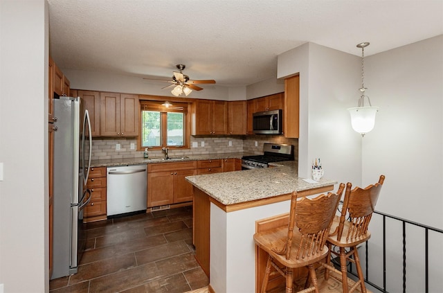 2726 Lakeland Dr, Urbandale, IA 50322 - kitchen featuring a peninsula, stainless steel appliances, backsplash, ceiling fan, and brown cabinetry