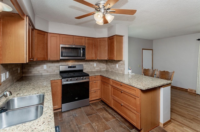 2726 Lakeland Dr, Urbandale, IA 50322 - kitchen featuring stainless steel appliances, a peninsula, a textured ceiling, tasteful backsplash, and dark wood-type flooring