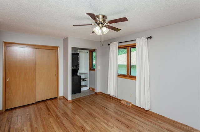 2726 Lakeland Dr, Urbandale, IA 50322 - unfurnished bedroom featuring light wood-style flooring, a textured ceiling, a closet, a ceiling fan, and a wall unit AC