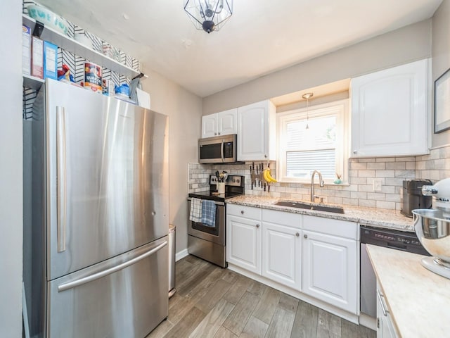 3934 Lincoln Place Dr, Des Moines, IA 50312 - kitchen featuring appliances with stainless steel finishes, backsplash, white cabinetry, light wood-style floors, and light stone countertops