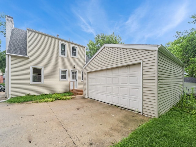 3934 Lincoln Place Dr, Des Moines, IA 50312 - view of front of house with an outbuilding, a chimney, a garage, and a shingled roof