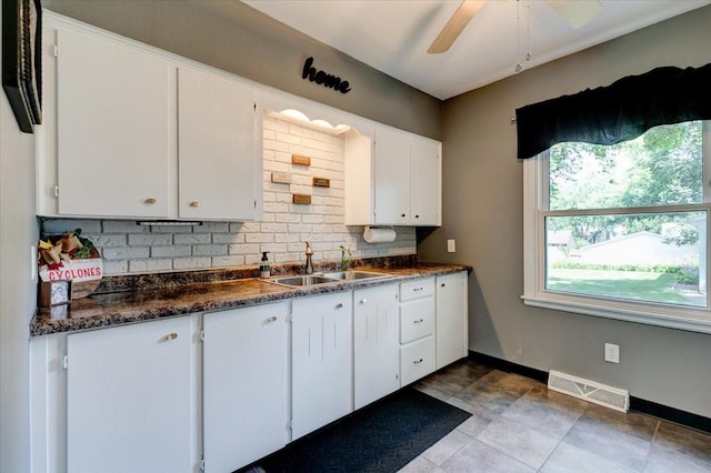 5613 College Ave, Des Moines, IA 50310 - kitchen featuring decorative backsplash, dark countertops, white cabinetry, a ceiling fan, and tile patterned floors