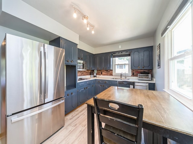 3303 Ashwood Dr, Urbandale, IA 50322 - kitchen with appliances with stainless steel finishes, light countertops, tasteful backsplash, and light wood-style floors