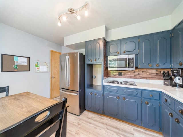 3303 Ashwood Dr, Urbandale, IA 50322 - kitchen with appliances with stainless steel finishes, tasteful backsplash, light wood-style flooring, light countertops, and blue cabinetry