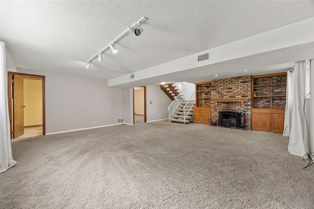 7005 Surrey Dr NE, Cedar Rapids, IA 52402 - unfurnished living room featuring a brick fireplace, carpet, stairs, rail lighting, and a textured ceiling