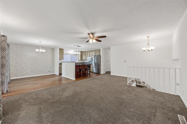 7005 Surrey Dr NE, Cedar Rapids, IA 52402 - unfurnished living room featuring a chandelier, dark colored carpet, ceiling fan, and dark wood-type flooring
