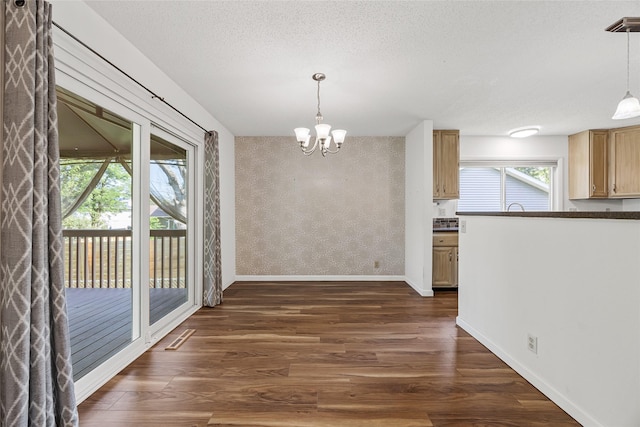 7005 Surrey Dr NE, Cedar Rapids, IA 52402 - unfurnished dining area featuring dark wood-style flooring, a chandelier, wallpapered walls, and a textured ceiling