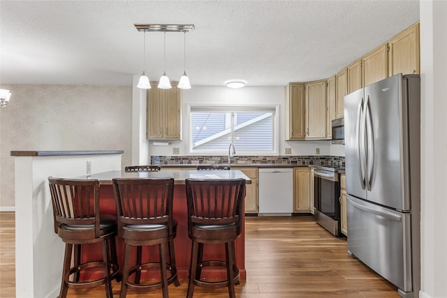 7005 Surrey Dr NE, Cedar Rapids, IA 52402 - kitchen featuring stainless steel appliances, dark wood finished floors, a breakfast bar area, pendant lighting, and a textured ceiling