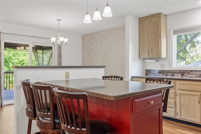 7005 Surrey Dr NE, Cedar Rapids, IA 52402 - kitchen with a chandelier, a kitchen breakfast bar, light brown cabinetry, and pendant lighting