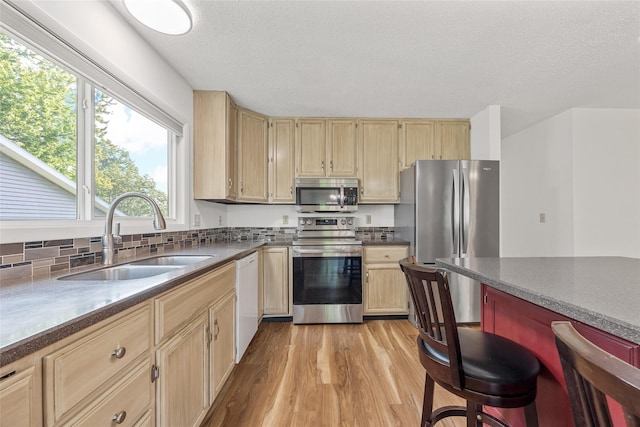 7005 Surrey Dr NE, Cedar Rapids, IA 52402 - kitchen featuring stainless steel appliances, light brown cabinets, light wood-style flooring, dark countertops, and a textured ceiling