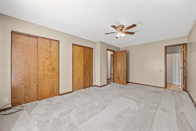 7005 Surrey Dr NE, Cedar Rapids, IA 52402 - unfurnished bedroom with two closets, light carpet, and ceiling fan