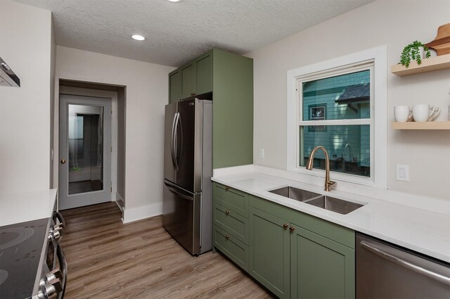 910 30th St, Des Moines, IA 50312 - kitchen with green cabinets, appliances with stainless steel finishes, light wood-style floors, light countertops, and a textured ceiling