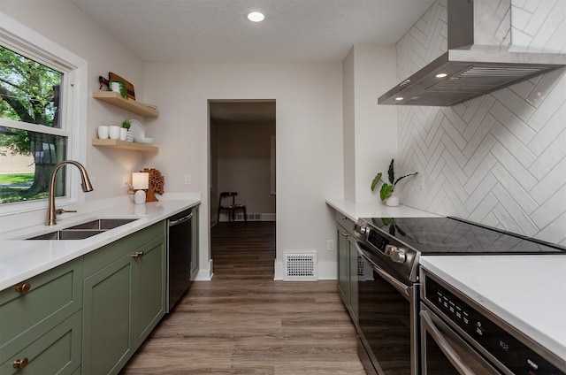 910 30th St, Des Moines, IA 50312 - kitchen featuring green cabinets, stainless steel appliances, wall chimney exhaust hood, light wood finished floors, and light countertops