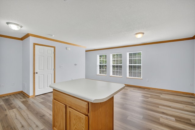 8302 Westown Pkwy Unit 7106, West Des Moines, IA 50266 - kitchen with ornamental molding, light wood-style flooring, a kitchen island, light countertops, and a textured ceiling