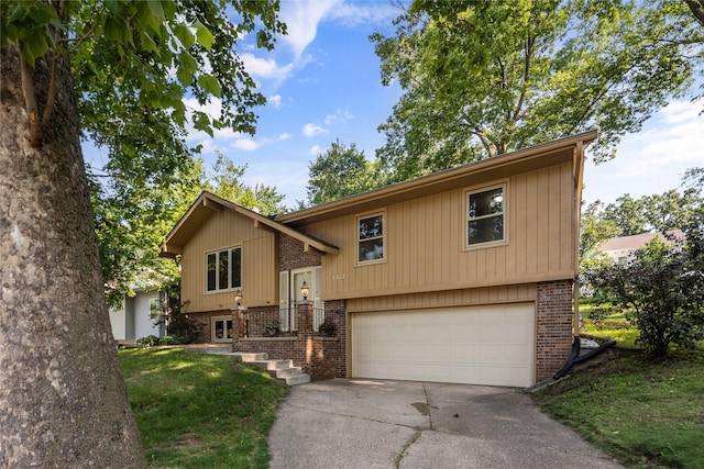 3312 Kinsey Ave, Des Moines, IA 50317 - split foyer home featuring concrete driveway, a garage, brick siding, and a front yard