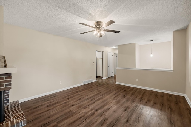 3312 Kinsey Ave, Des Moines, IA 50317 - unfurnished living room with dark wood-type flooring, a ceiling fan, a brick fireplace, and a textured ceiling