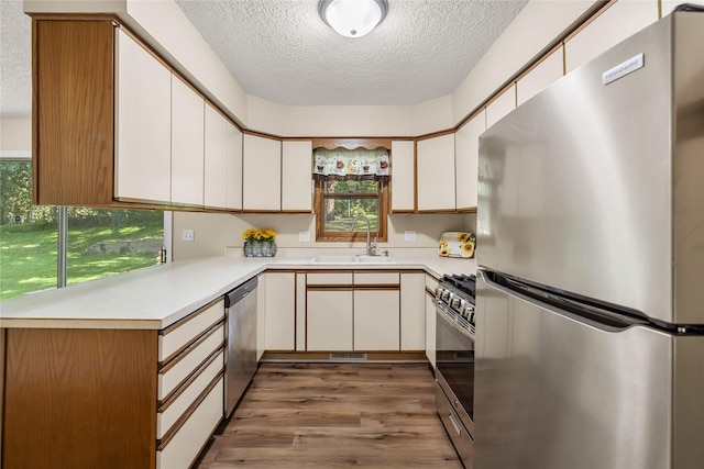 3312 Kinsey Ave, Des Moines, IA 50317 - kitchen featuring appliances with stainless steel finishes, a textured ceiling, light countertops, light wood finished floors, and white cabinetry