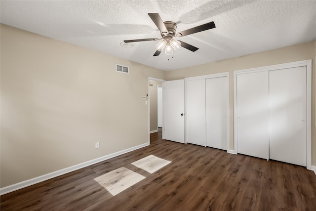 3312 Kinsey Ave, Des Moines, IA 50317 - unfurnished bedroom featuring two closets, wood finished floors, ceiling fan, and a textured ceiling