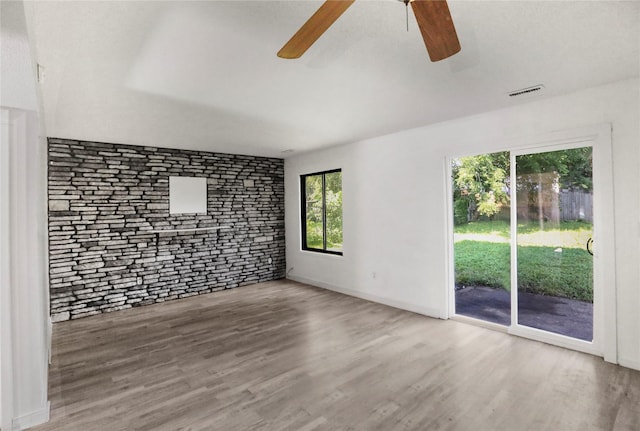 1356 E 17th Ct, Des Moines, IA 50316 - unfurnished living room featuring ceiling fan, wood finished floors, and brick wall