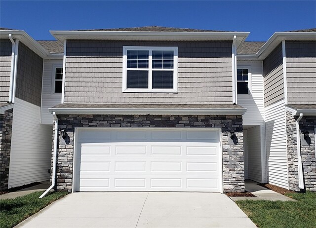 2109 Bugge Dr, Adel, IA 50003 - view of front of home with stone siding, a garage, driveway, and a shingled roof