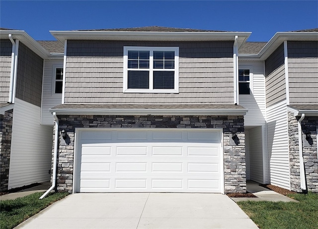 2103 Bugge Dr, Adel, IA 50003 - view of front of home featuring stone siding, a garage, concrete driveway, and a shingled roof