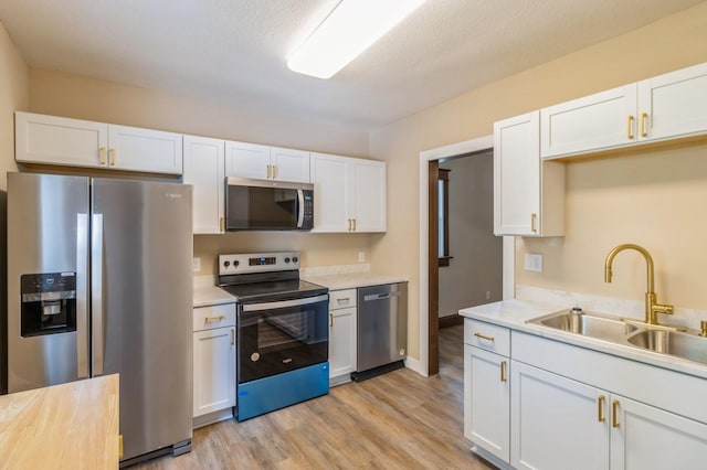 1141 Douglas Ave, Des Moines, IA 50313 - kitchen featuring appliances with stainless steel finishes, light wood finished floors, light countertops, and white cabinetry