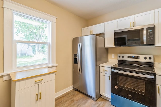1141 Douglas Ave, Des Moines, IA 50313 - kitchen with stainless steel appliances, light countertops, light wood finished floors, and white cabinetry
