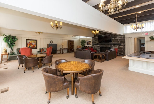 3663 Grand Ave Unit 501, Des Moines, IA 50312 - carpeted dining area featuring a chandelier, a towering ceiling, and a stone fireplace